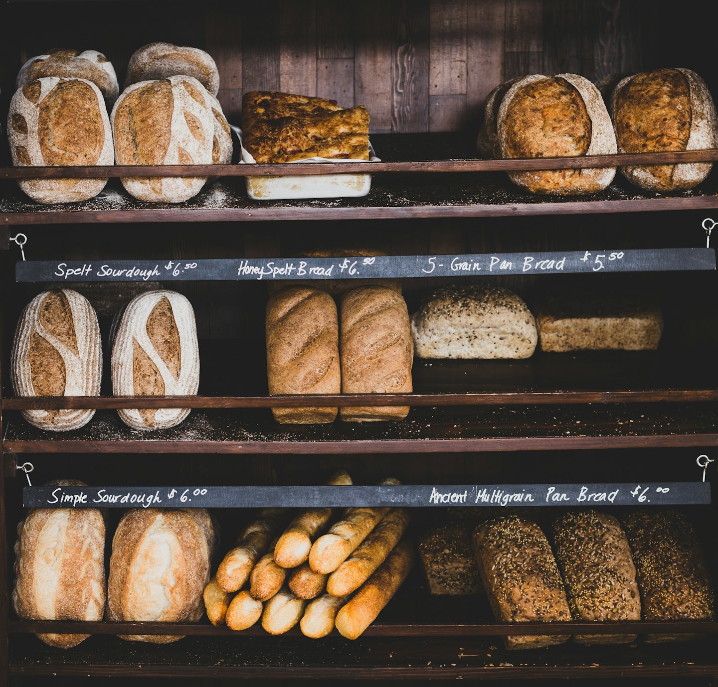 Freshly baked artisan bread loaves on rustic wooden shelves.