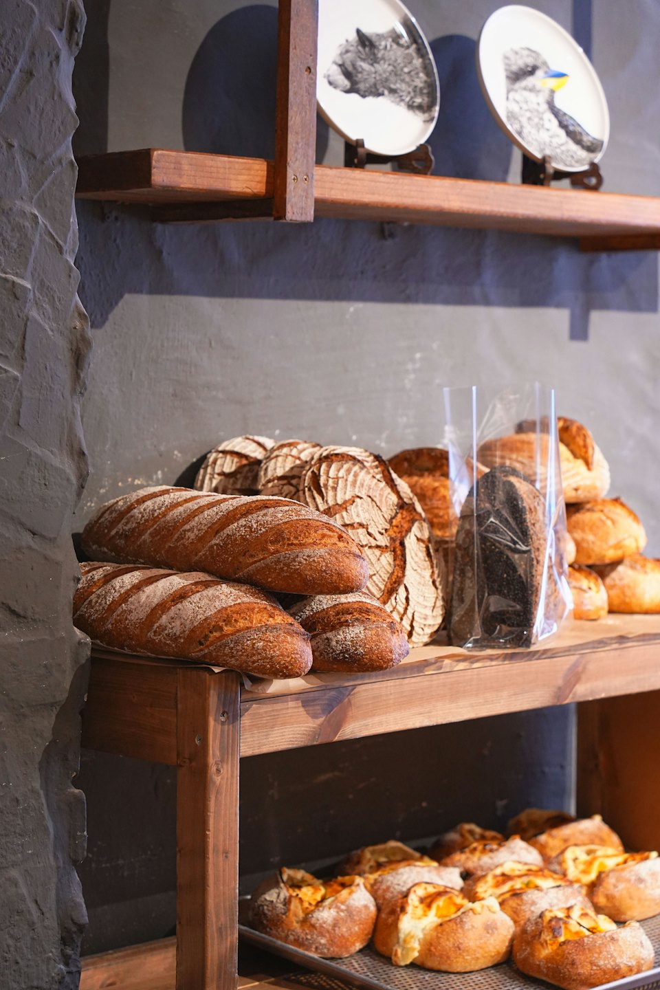 Artisanal bread loaves displayed on wooden bakery shelves.