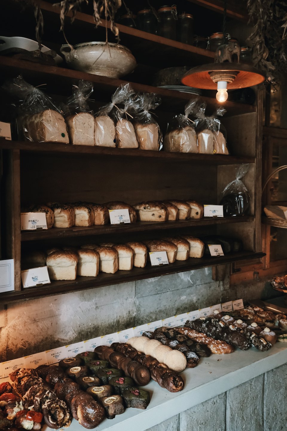 Wooden shelves and counter displaying fresh bread and pastries.
