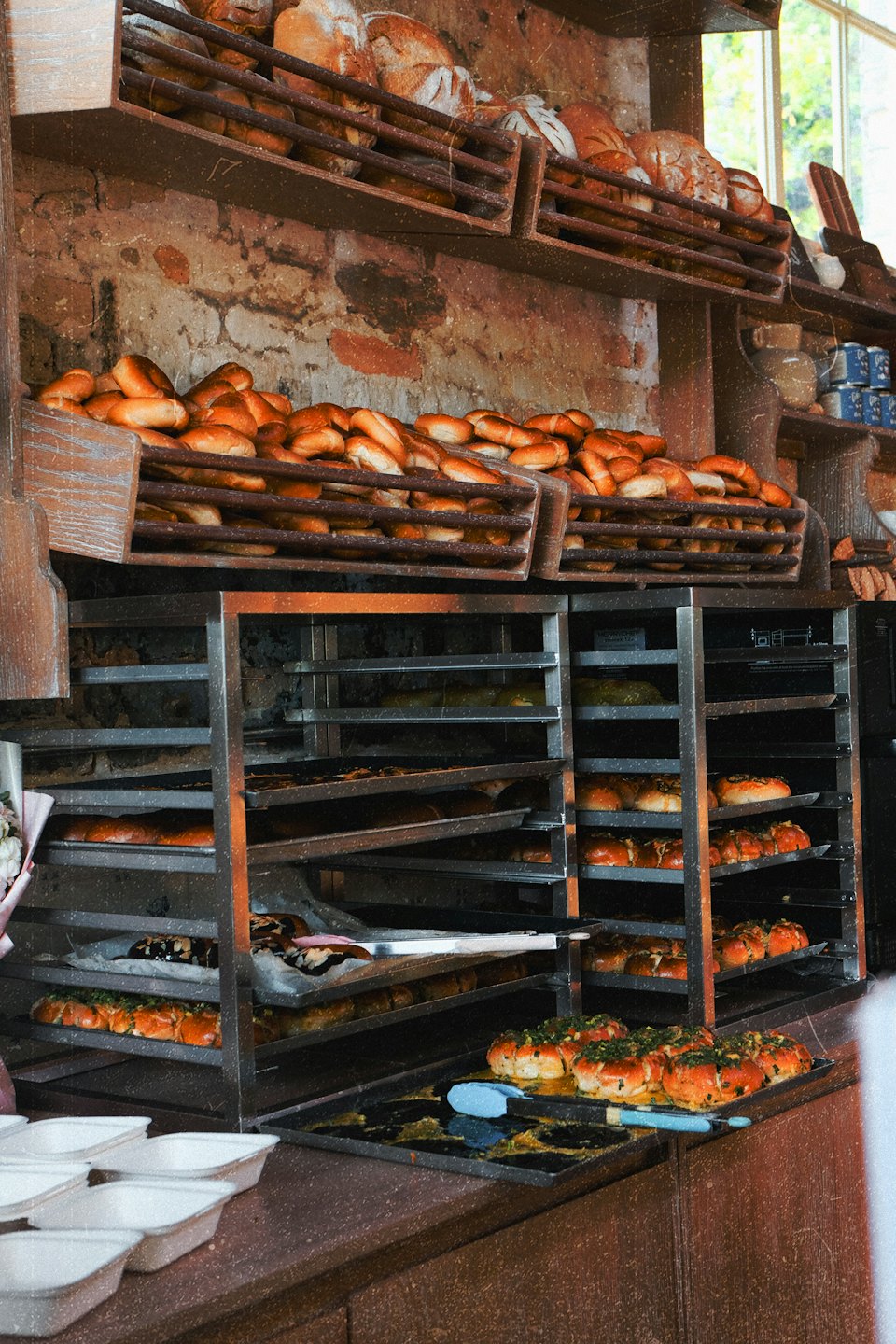 Fresh loaves and bread rolls sit on wooden bakery shelves.