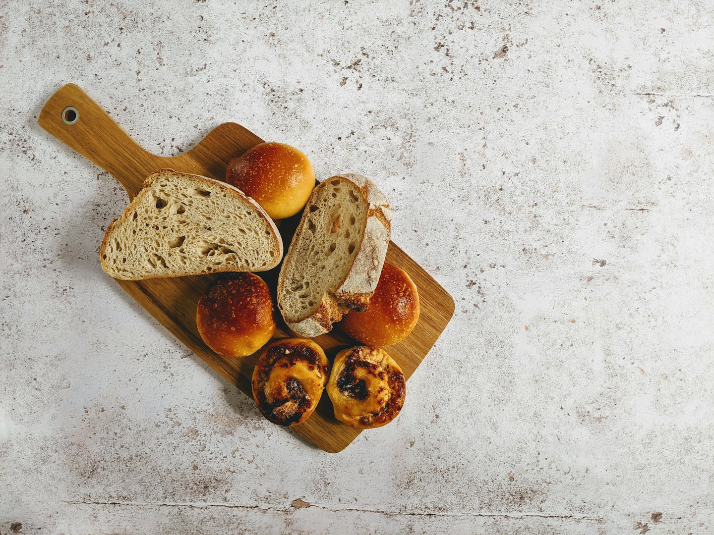 Freshly baked artisan breads and pastries on a wooden cutting board.