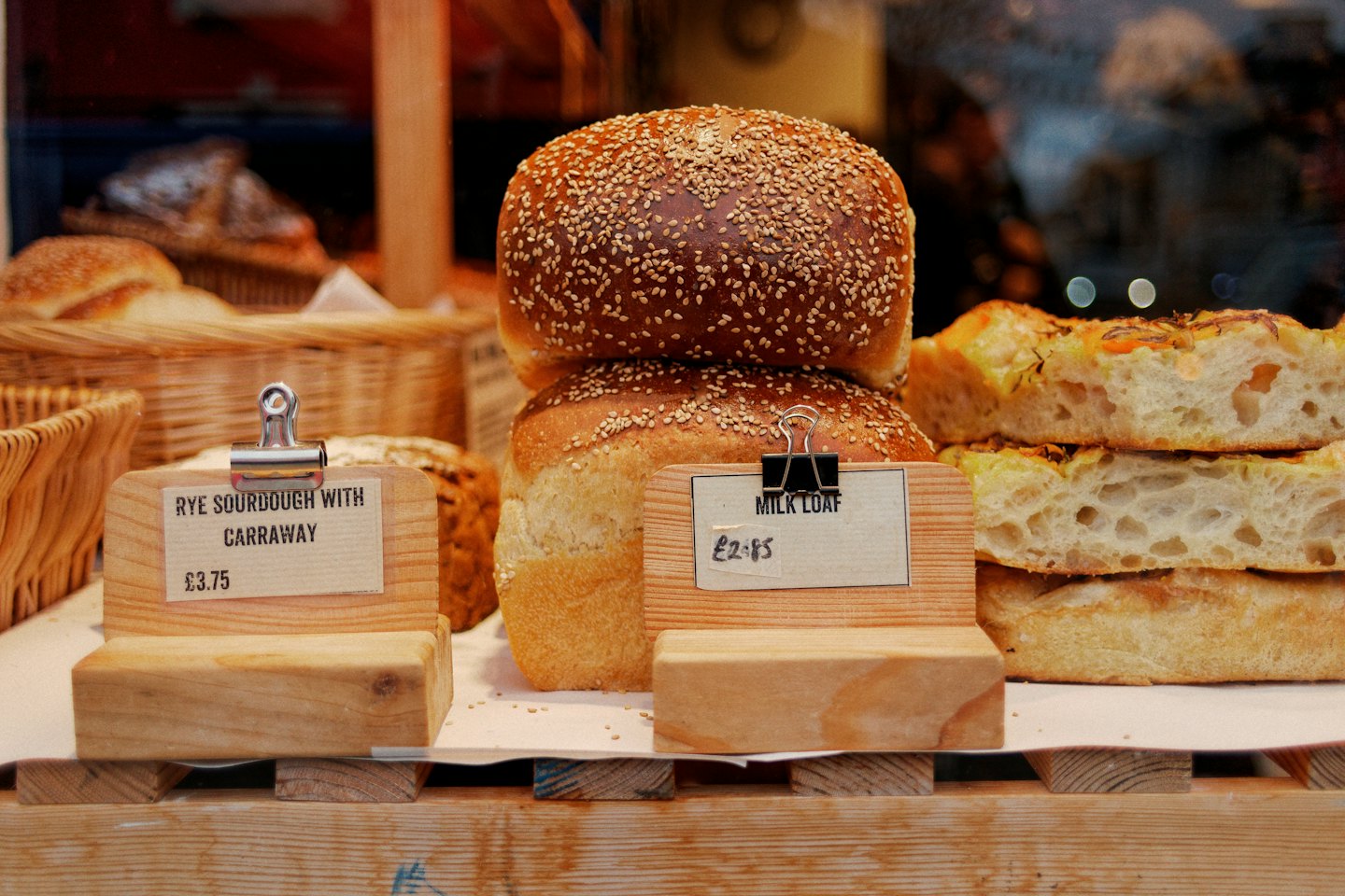 Freshly baked loaves of bread and focaccia on wooden display stands.