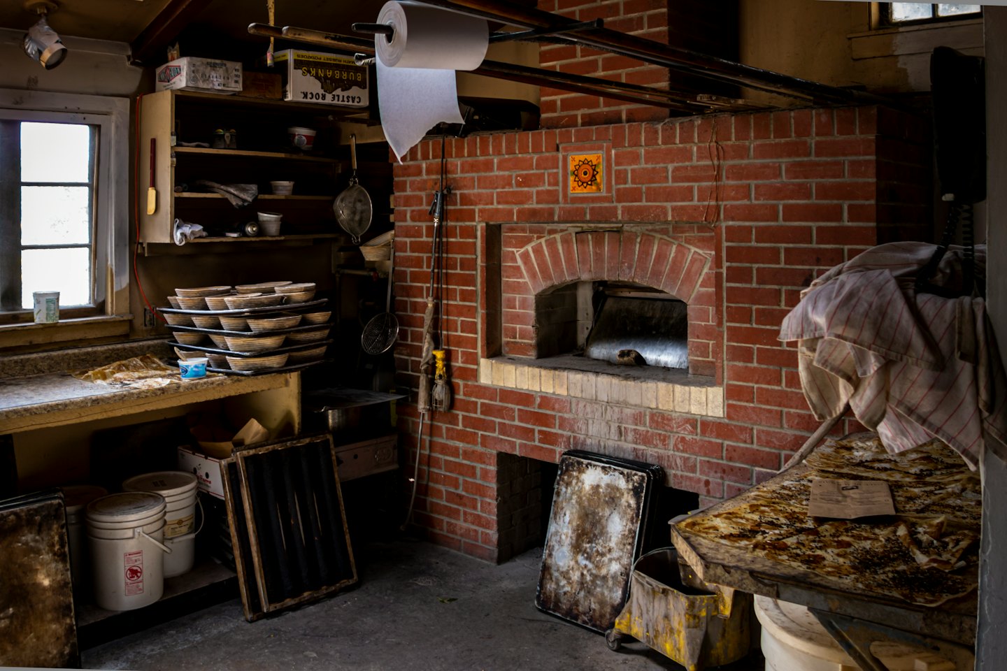 Rustic bakery kitchen featuring a large red brick oven.