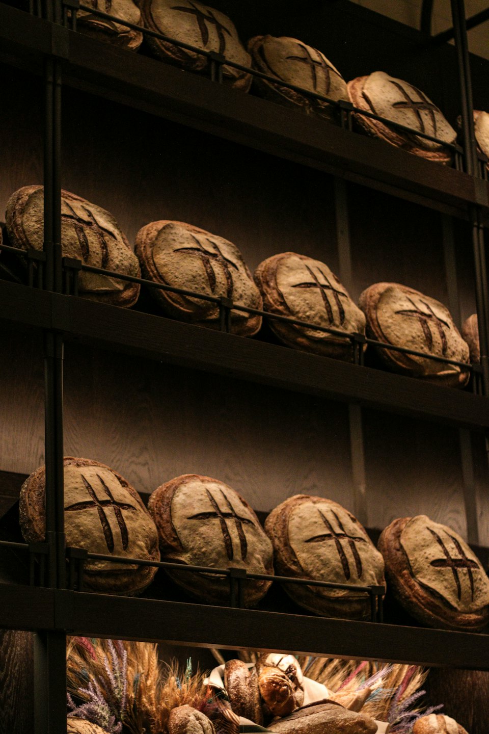 Round sourdough loaves rest on dark tiered bakery shelves.