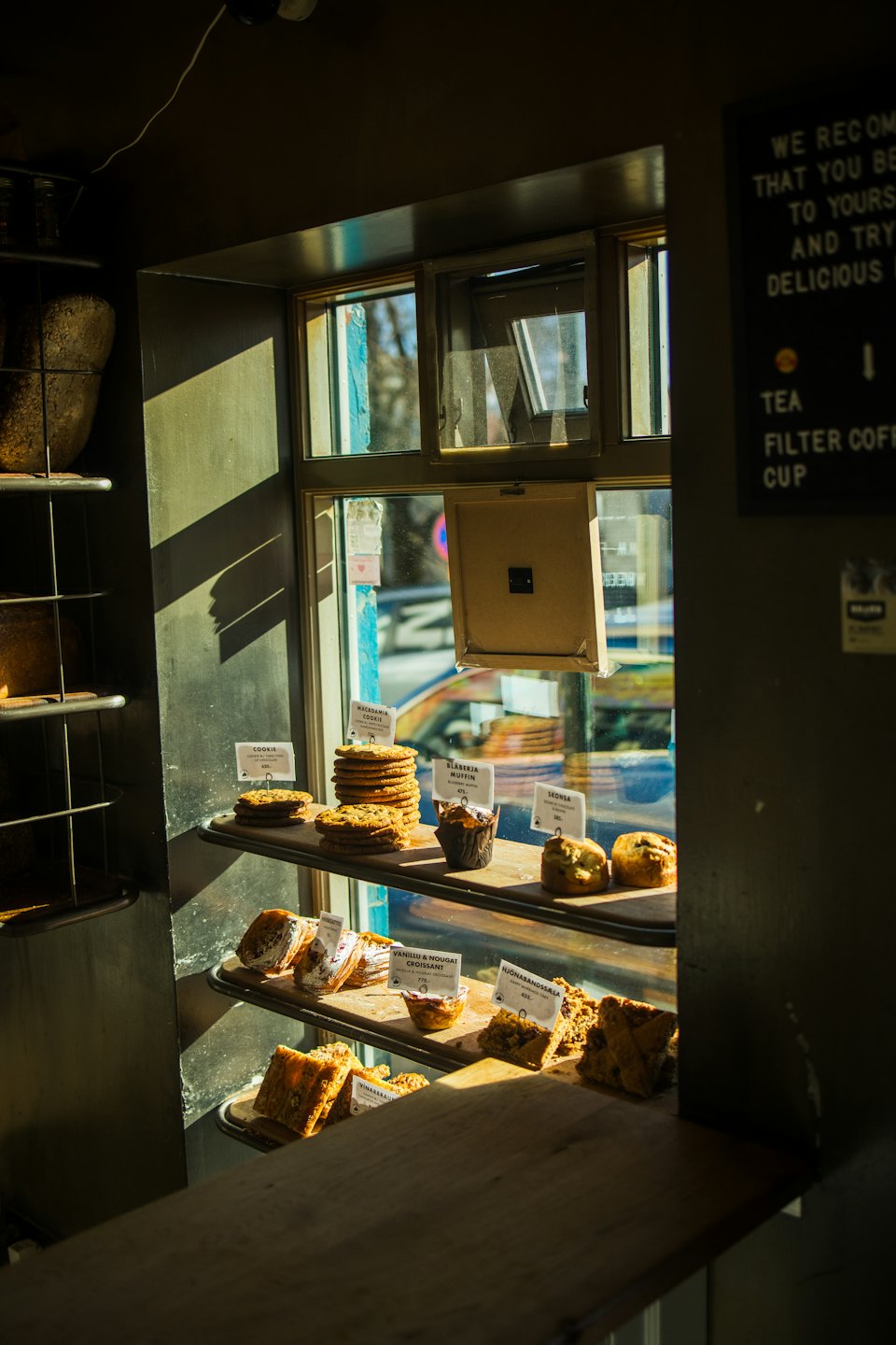 Assorted fresh pastries displayed on wooden shelves inside a bakery.
