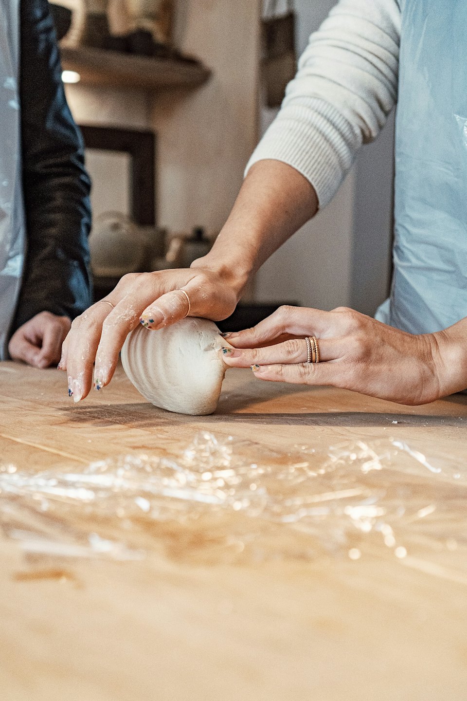 Hands dusted with flour knead dough on a wooden table.